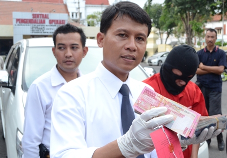 Kasat Reskrim Polrestabes Surabaya AKBP Sumaryono membawa sejumlah barang bukti berupa uang yang hendak dimiliki tersangka. (FOTO : Parlin/surabayaupdate)
