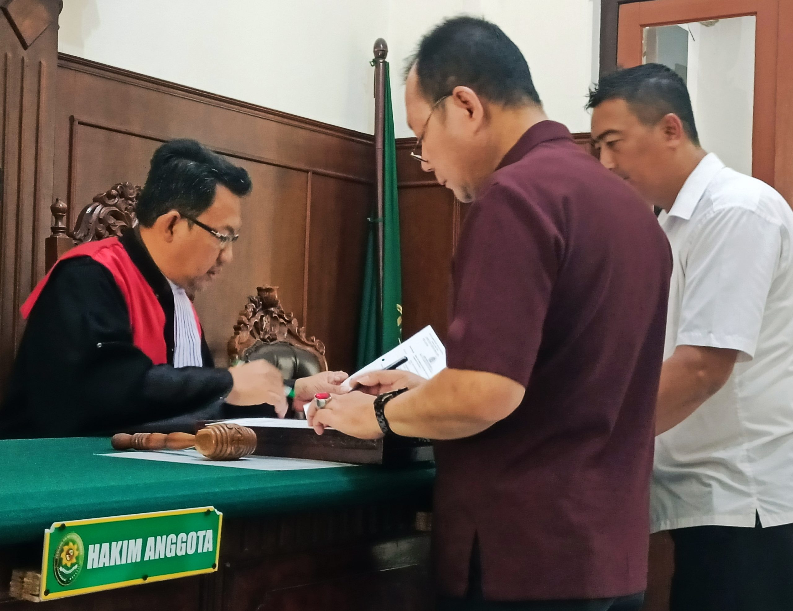 Dihadapan hakim, Dr. Johan Widjaja memeriksa bukti surat tambahan yang diserahkan kuasa hukum Unit I Subdit IV Ditreskrimum Polda Jatim. (FOTO : parlin/surabayaupdate.com)